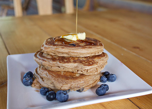 Stack of pancakes with syrup being poured on them