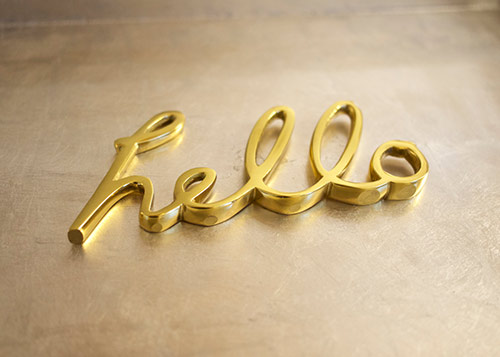 Gold hello sculpture sitting on a metal tray